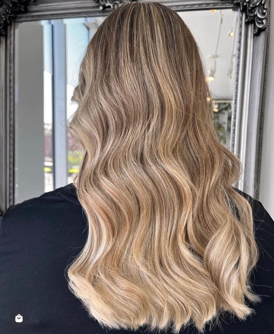 Sandy blonde balayage with long beachy waves — Salon Fiorella
